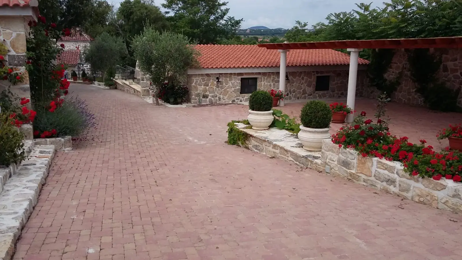 Popločano dvorište kamene kuće crvenim opločnicima s cvjetnim rubom