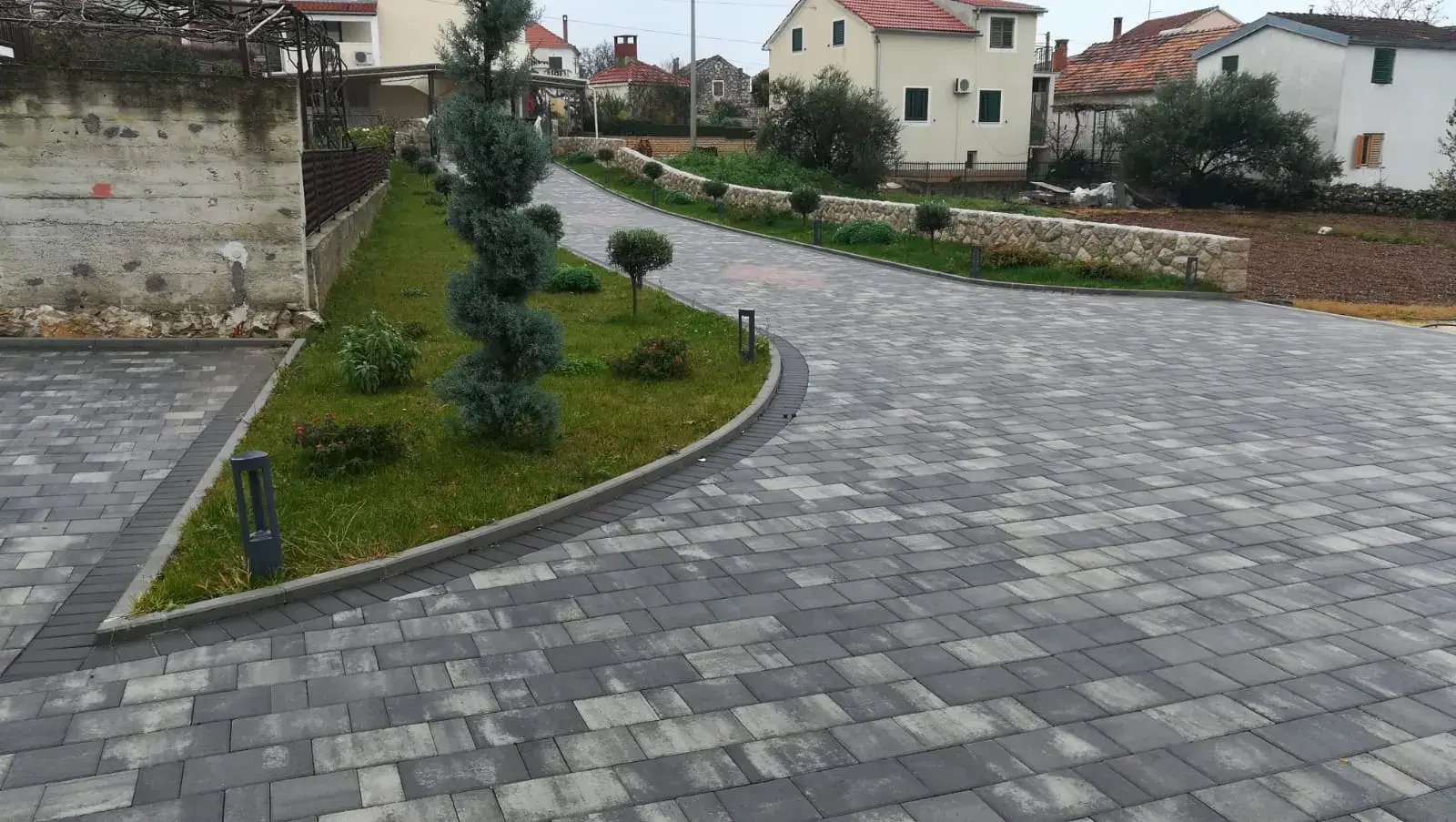 Popločano dvorište i prilaz sivim opločnicima sa zelenom gredicom