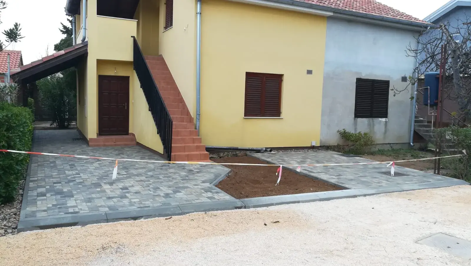Popločano dvorište sivim opločnicima uz obiteljsku kuću