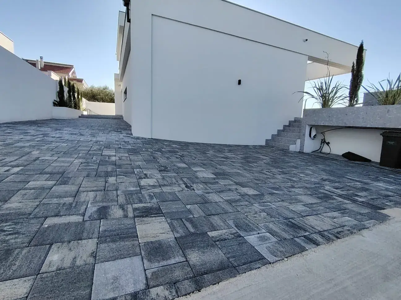 Popločan prilaz i dvorište tamnosivim betonskim opločnicima uz modernu kuću