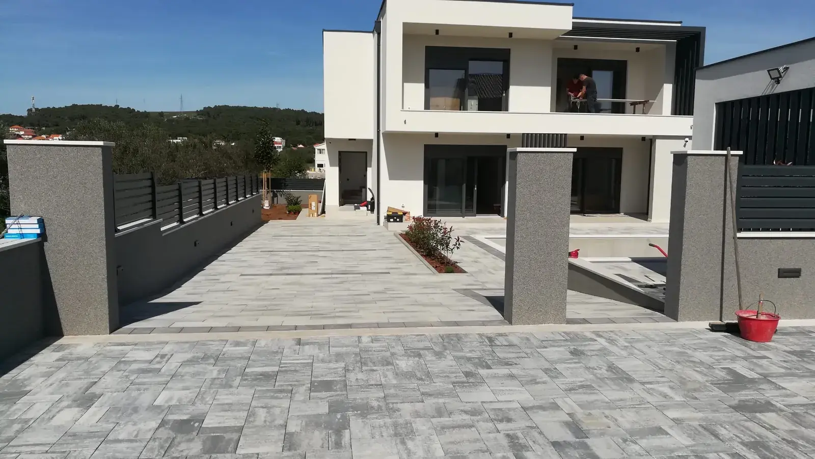 Popločan prilaz sivim opločnicima uz modernu kuću