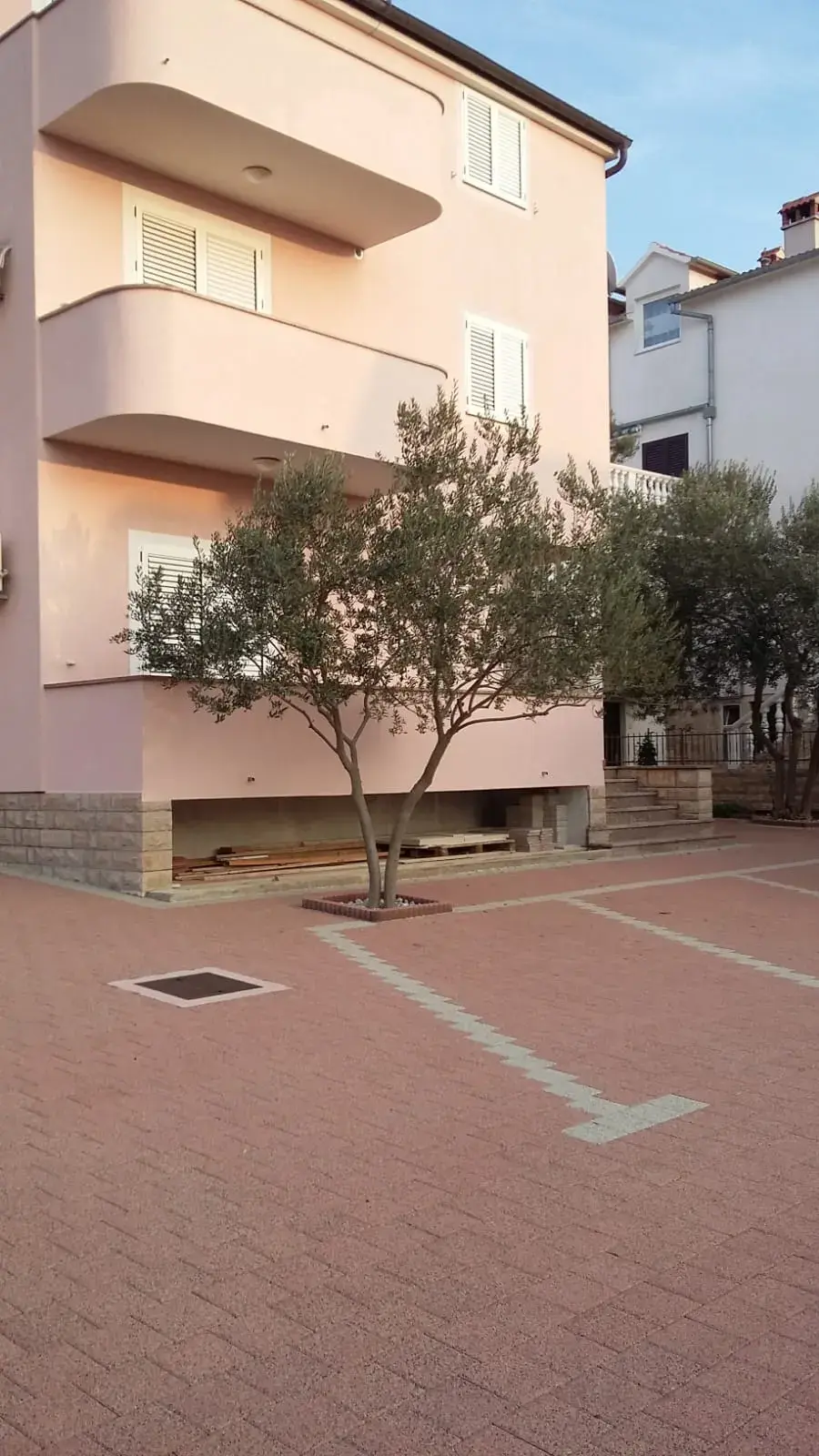 Popločan parking s označenim parkirnim mjestima crvenim opločnicima